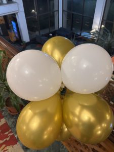 A close-up view of a cluster of balloons in a combination of white and shiny gold. 