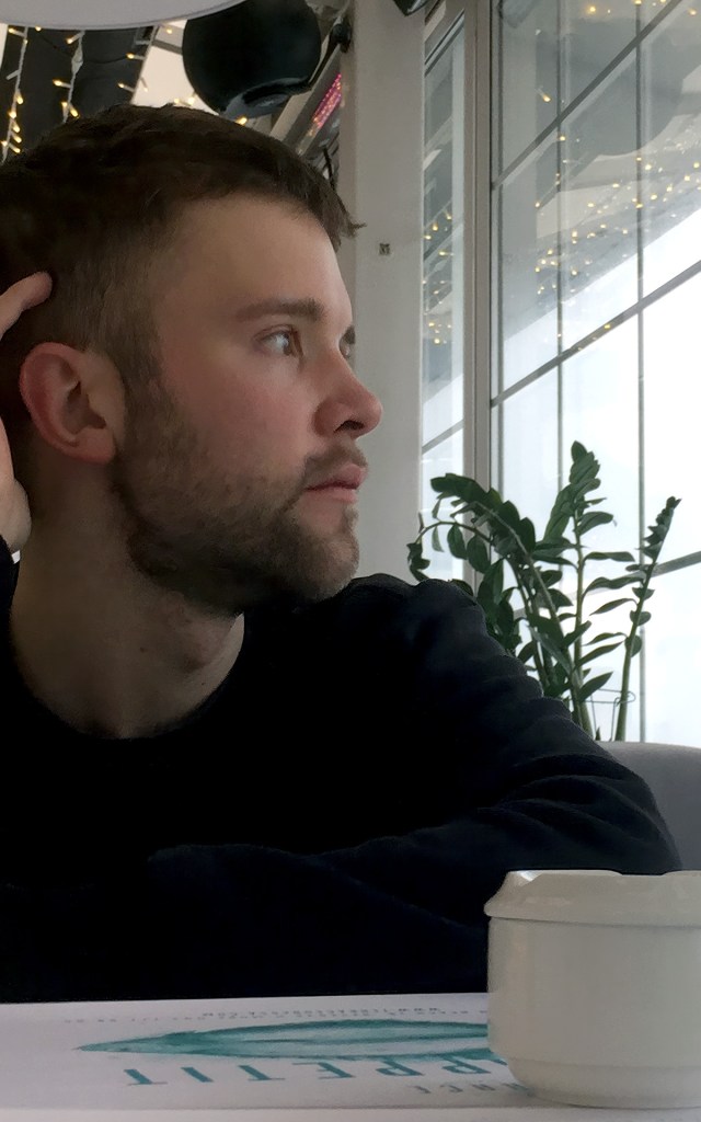 Artemy reflecting on his learning as he looks outside of a window in a cafe
